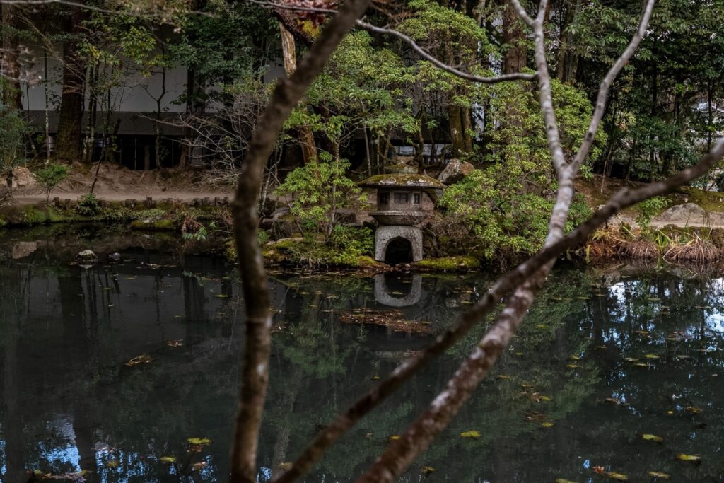 A traditional Japanese stone lantern sitting quietly on the edge of a reflection pond, embodying timeless Zen design principles during the Kyoto private culture tour.