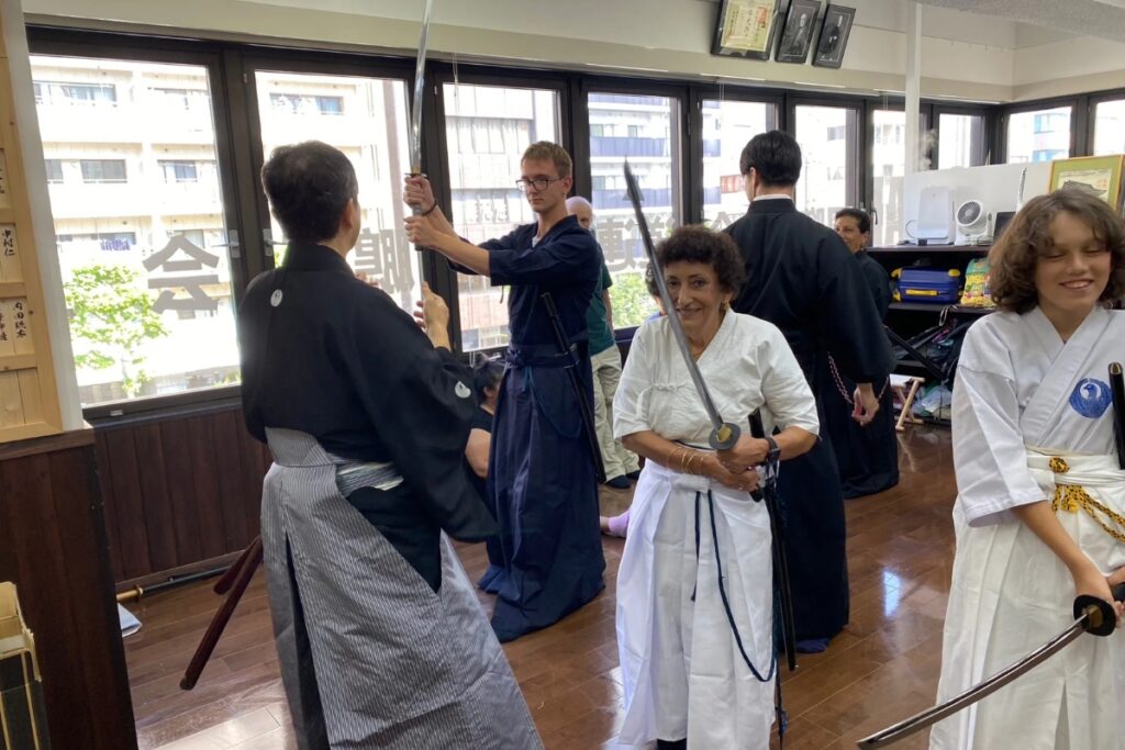 Family of guests holding swords and smiling during a hands-on Tokyo Iaido experience in a dojo