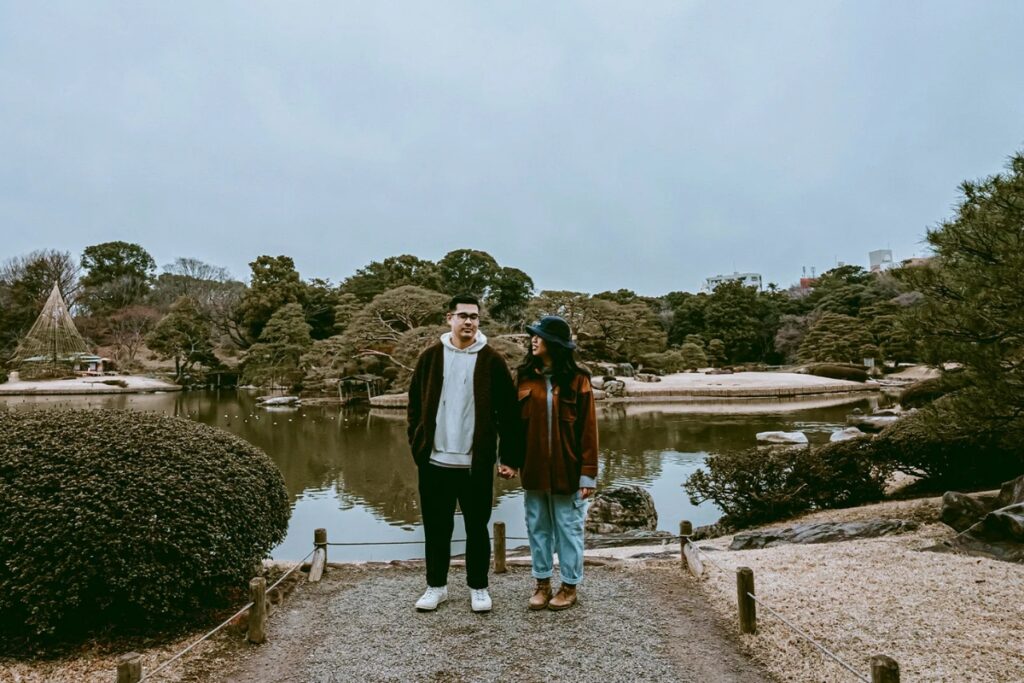 Couple holding hands beside a tranquil Japanese garden pond photographed by a Tokyo private photographer