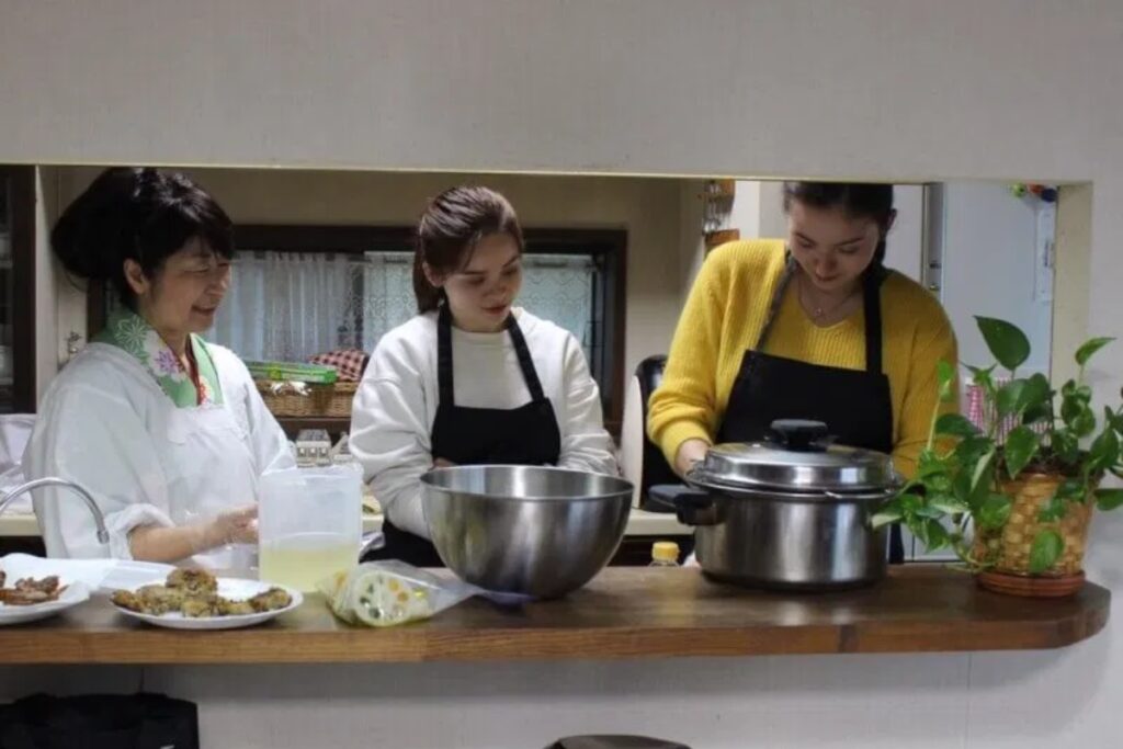 Travelers cooling sushi rice in a hangiri wooden bowl during a private Tokyo sushi cooking class