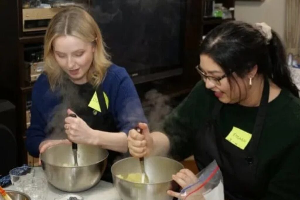 Two guests mixing ingredients over steaming bowls at a hands-on Tokyo vegan cooking class