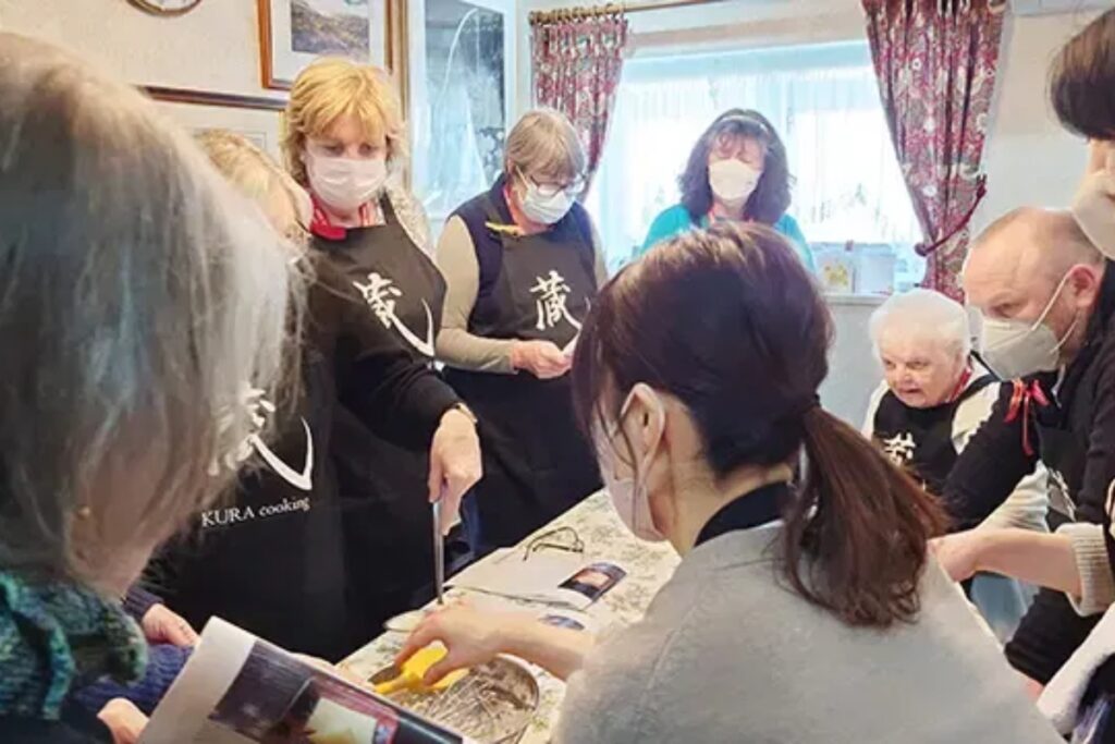 International guests in aprons learning to cook traditional dishes with their host at a Nagoya cooking class