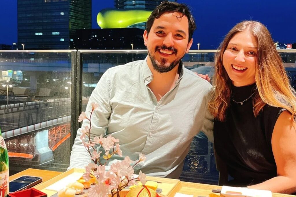 Happy couple smiling with a Tokyo night skyline view at their Tokyo sushi making experience