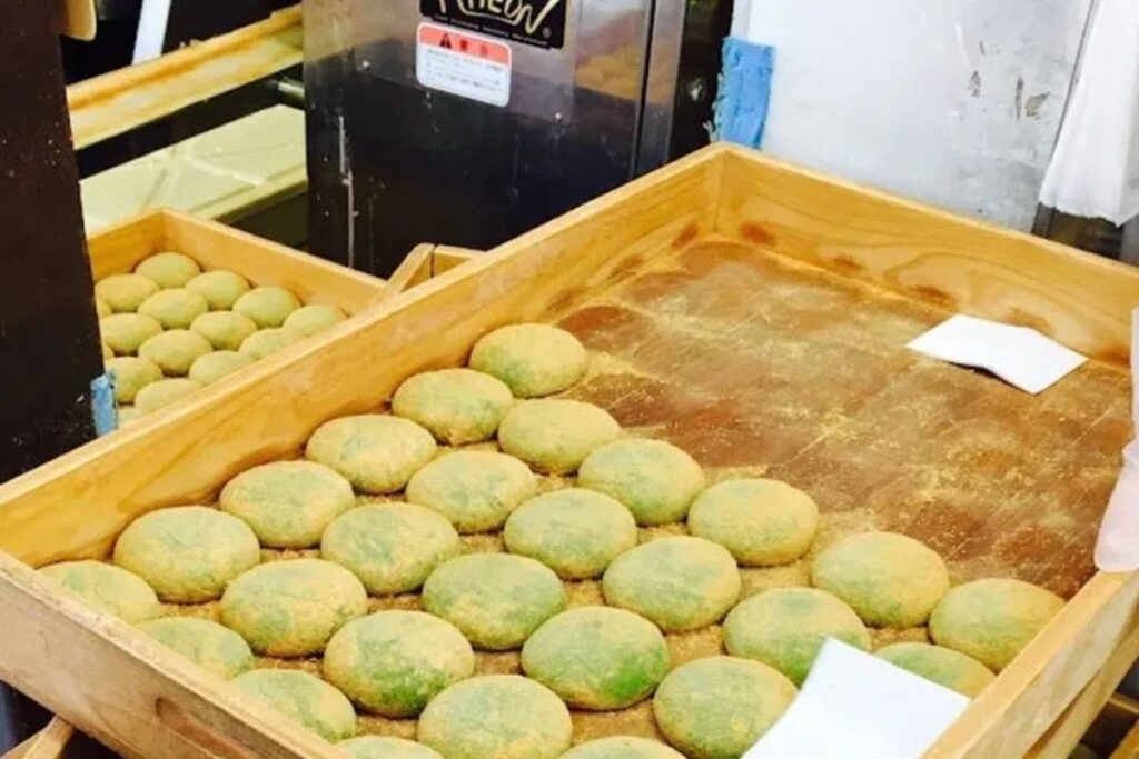 Freshly pounded green sweet rice cakes displayed in wooden trays.