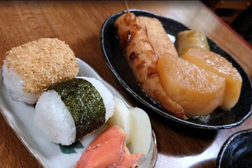 A traditional Japanese lunch plate featuring a rice ball and savory side dishes.