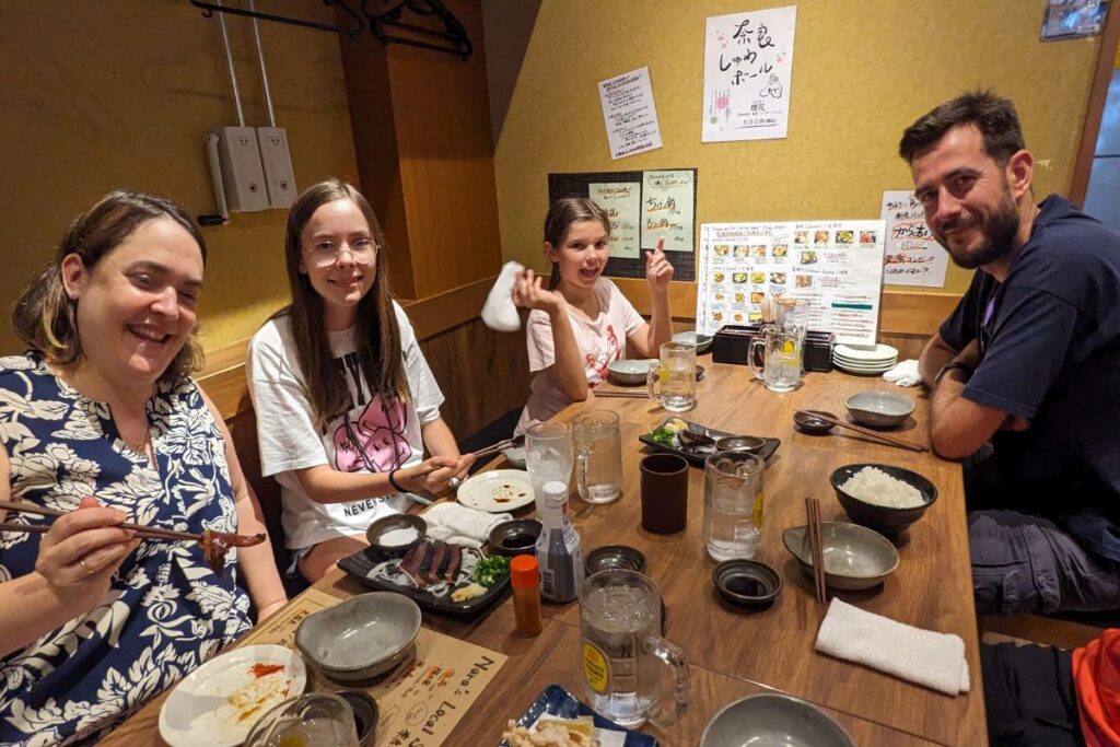 A smiling family of four sitting at a wooden table sharing a delicious traditional restaurant meal.