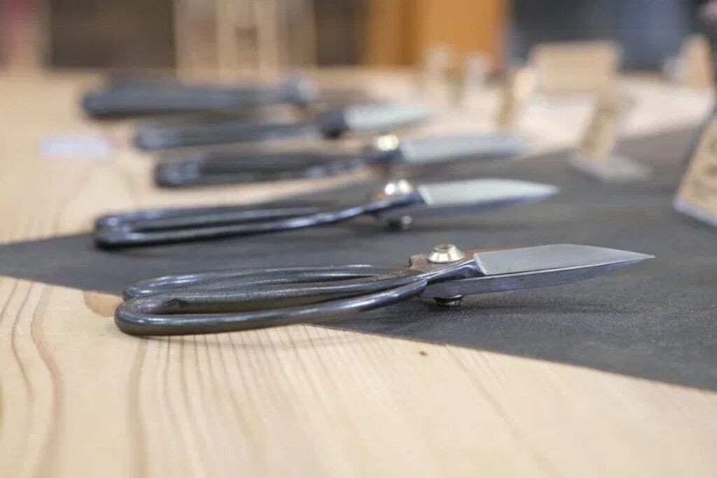 Several shiny, high-quality kitchen blades displayed neatly on a wooden counter.