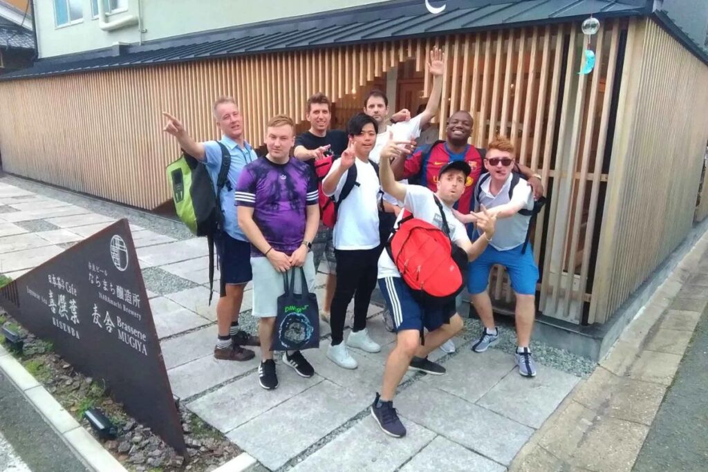 A group of excited travelers posing together outdoors during a Nara sake and food tour.