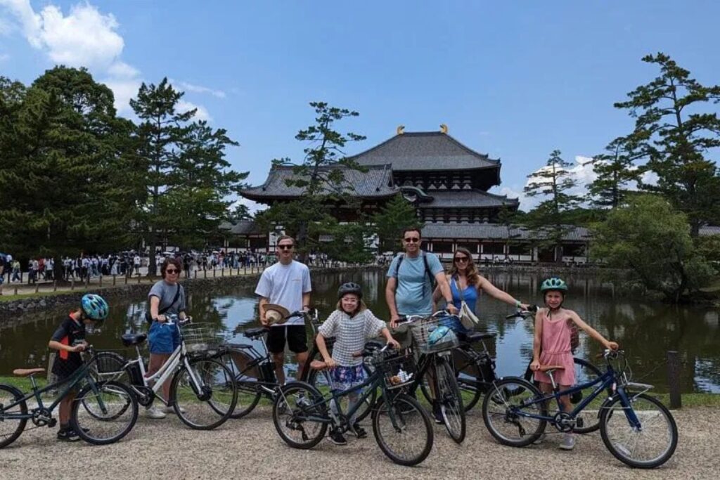 A group posing with their bicycles next to a peaceful pond during a Nara highlights E-bike tour.