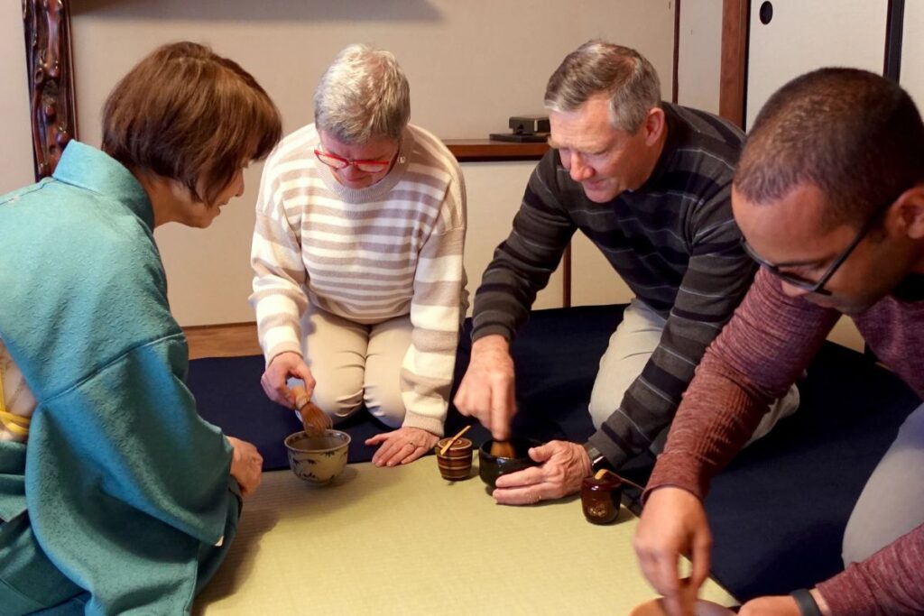 A group of travelers learning how to whisk matcha with a local instructor during a Kyoto Machiya tea ceremony.