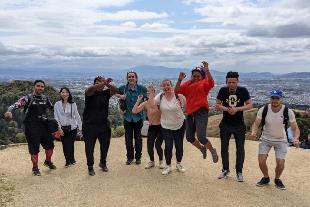A group of people celebrating at a mountain summit overlook during a Nara nature bike tour.