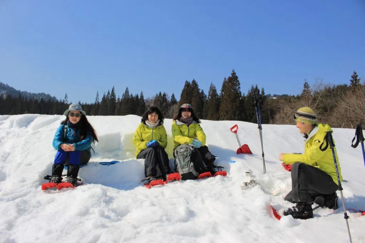 Guests relaxing in the deep snow during a gentle and easy-paced Hida snowshoeing tour.