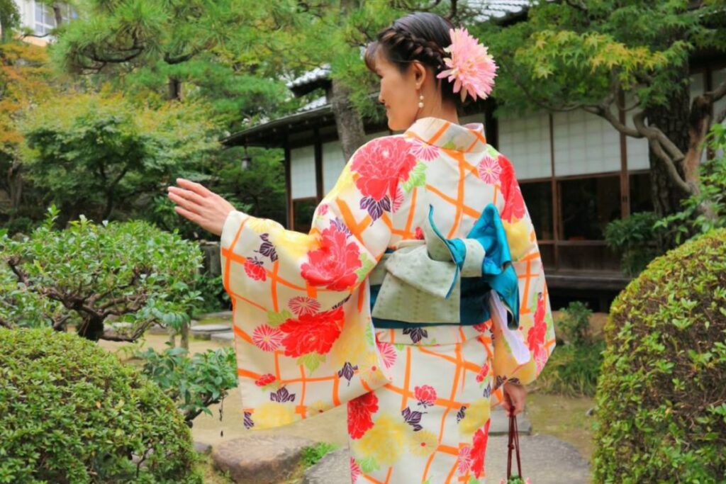 A guest enjoying the scenic garden stroll portion of the Kimono and matcha experience Nagoya while wearing an authentic white and red floral kimono.