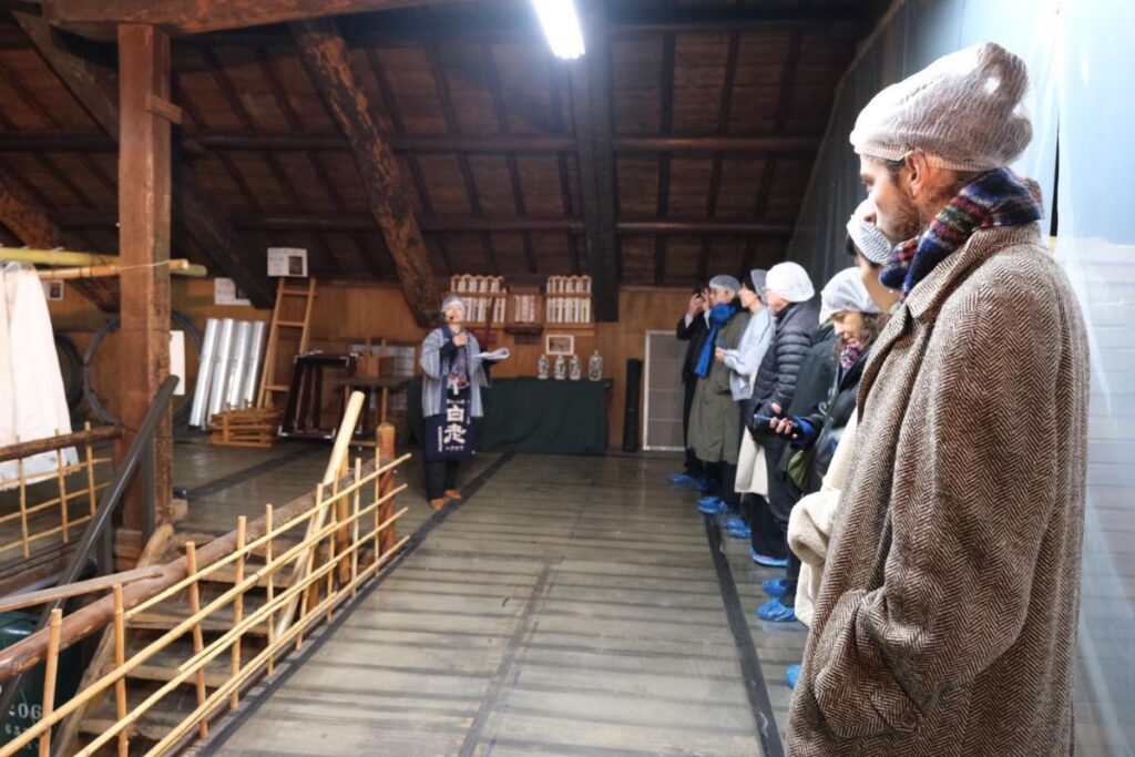 Visitors taking an exclusive owner-led tour of the historic 1848 facility during the sake label making experience.