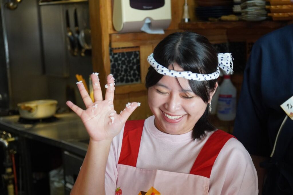 A guest laughing as sushi rice sticks to her hand, showing the fun and interactive learning process of a Nagoya sushi making workshop.