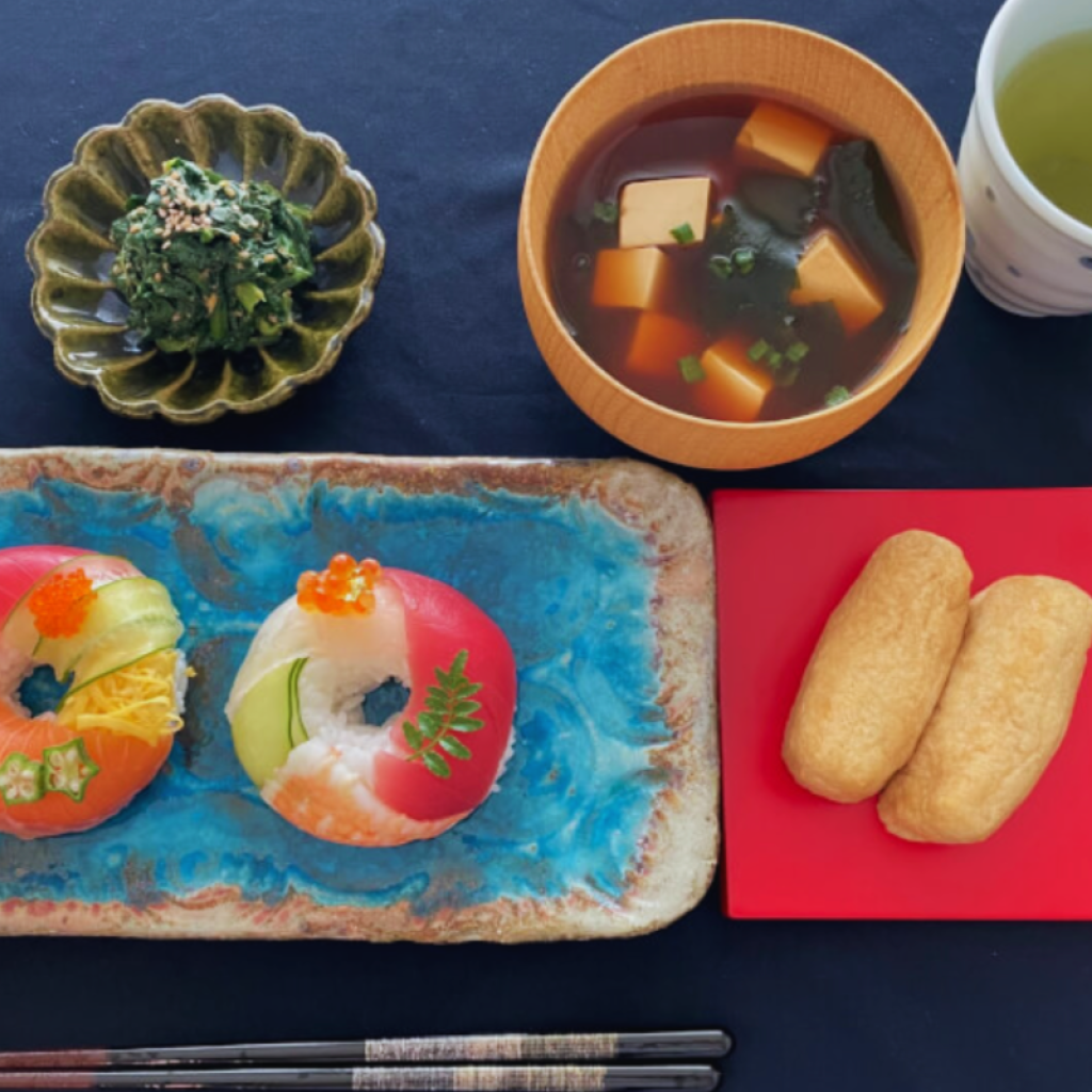 Artfully arranged doughnut sushi with colorful seasonal toppings served alongside traditional Japanese side dishes and soup.